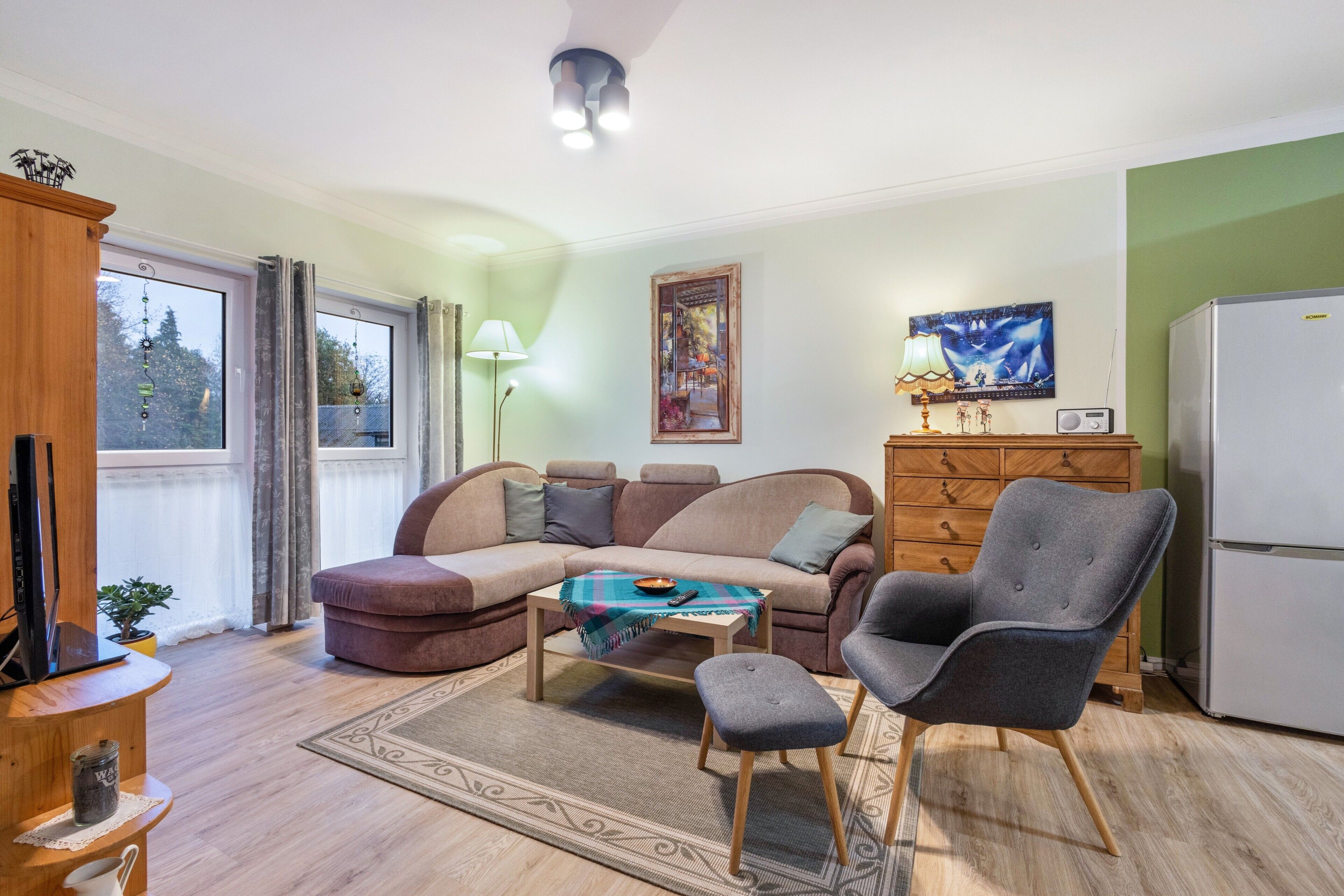 A living room with a sofa, armchair, coffee table, and a television.