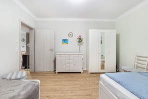 Une chambre à coucher comprenant un lit, une commode, une armoire, une chaise, une petite table et une horloge murale.