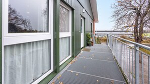 A building with large windows, a metal balcony, and a view of a tree and distant landscape.