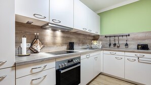A modern kitchen with white cabinets, a stainless steel oven, and a wooden backsplash.