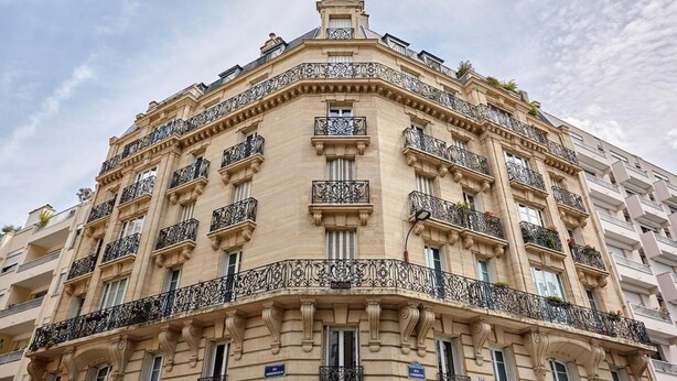 Un immeuble à plusieurs étages, doté de balcons richement décorés et d’un style architectural classique.