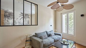 Un salon avec un canapé gris, une table basse ronde et une grande œuvre d’art encadrée accrochée au mur.