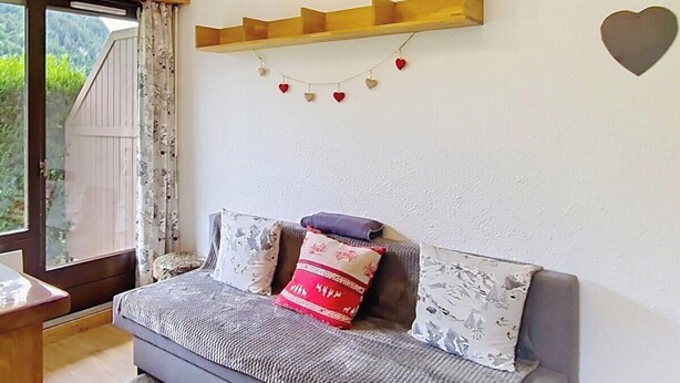 A cozy room with a sofa, a wooden shelf with heart decorations, and a window with curtains. - Toison Blanche TBC45 COSY & Mountain 4 Pers (Châtel)