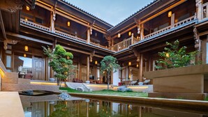 A traditional wooden building with a courtyard, stone steps, and a small pond.