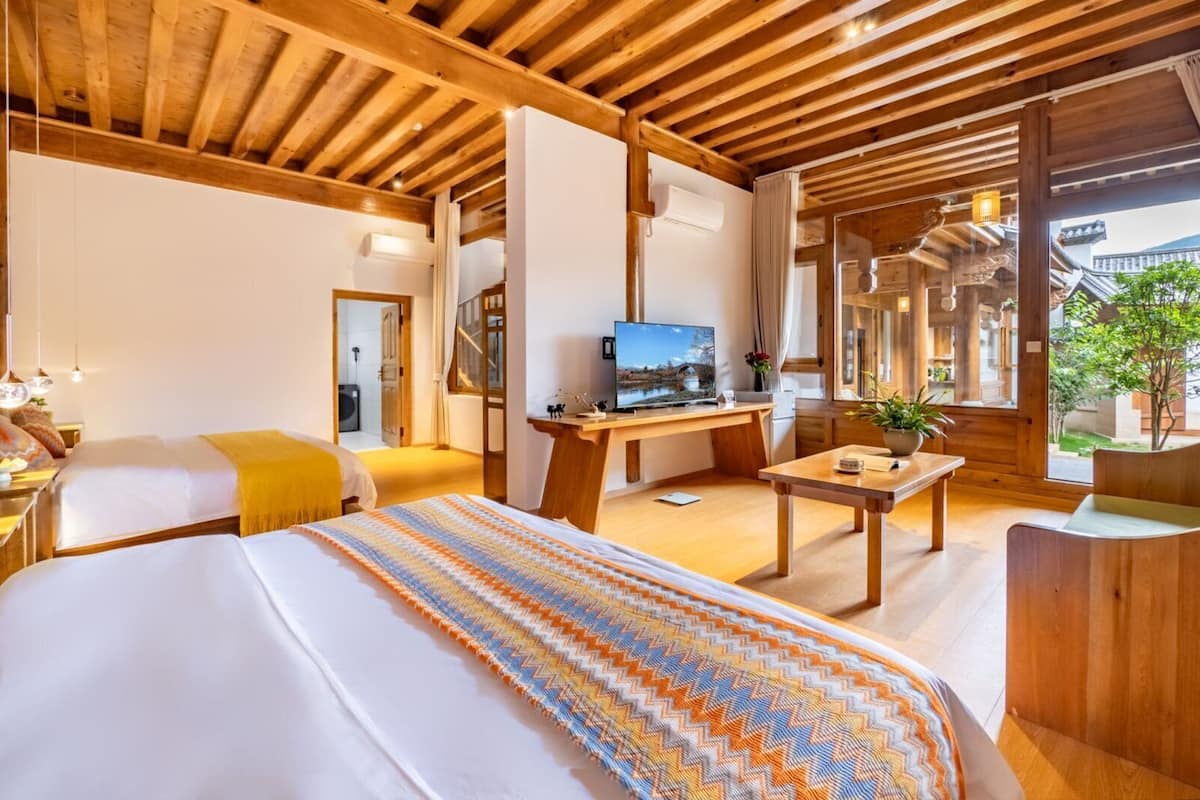 Een hotelkamer met een bed, een bureau met een computer, een televisie en uitzicht op traditionele architectuur.
