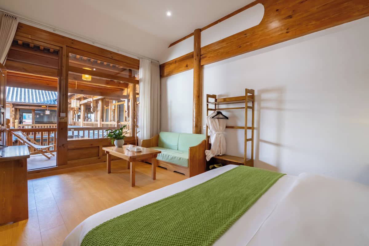 Een houten kamer met een bed, een bank, een tafel en een kledingrek.