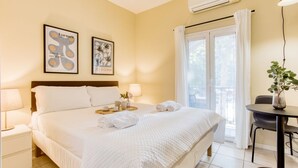 A hotel room with a large bed, two bedside tables, a small table with a vase, and a window with curtains. - Easylife - Studio with balcony in Porta Romana (Milano)
