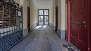 A hallway with a red door, a metal gate, and a view through a glass door. - Easylife - Studio with balcony in Porta Romana (Milano)