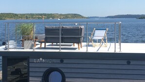 Una terraza con un sofá, una silla de descanso y una planta en maceta.