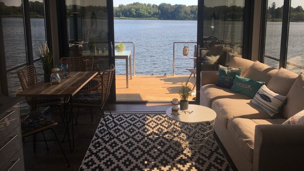 Un interior moderno con comedor, sofá y vistas a un lago.