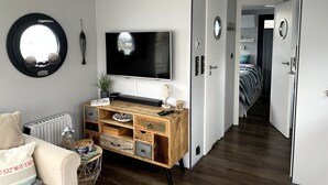 Una sala de estar moderna con televisor, mueble de madera para entretenimiento y una zona de estar acogedora.