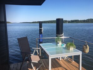 Une terrasse avec une table en verre, une chaise et un pot de fleurs.