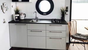 Una cocina moderna con horno empotrado, un espejo redondo sobre el lavamanos y vistas al exterior a través de un ventanal grande.