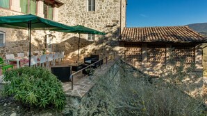 A stone building with a terrace, outdoor seating, and a view of the countryside. - Apartment in a farmhouse with swimming pool (Assisi)