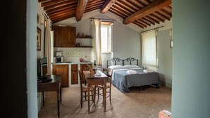 A cozy room with a bed, a desk, and a kitchenette. - Apartment in a farmhouse with swimming pool (Assisi)