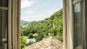 Une vue depuis une fenêtre donnant sur une vallée verdoyante et luxuriante, avec une piscine.