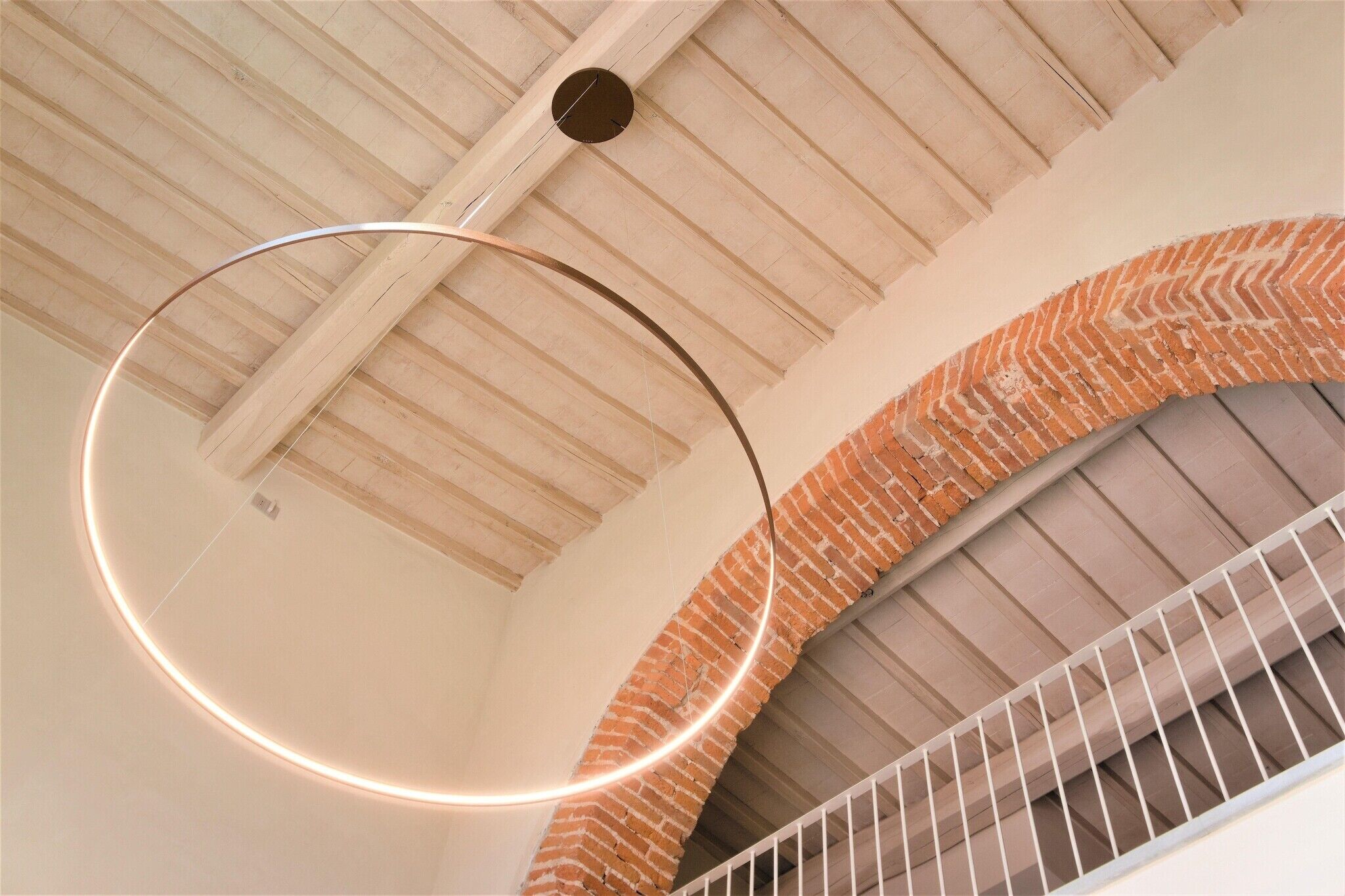 A spiral staircase with a brick wall and a wooden ceiling.