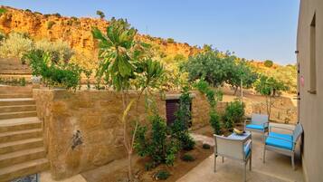 A patio with outdoor furniture, a stone wall, and a view of a rocky hillside.