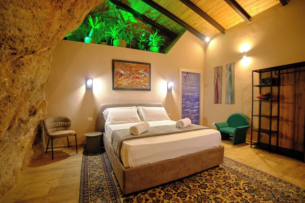 Une chambre à coucher comprenant un lit, une chaise, une petite table et un mur décoré d’œuvres d’art.