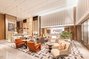 A spacious lobby with a bar area, seating arrangements, and a large window providing natural light.