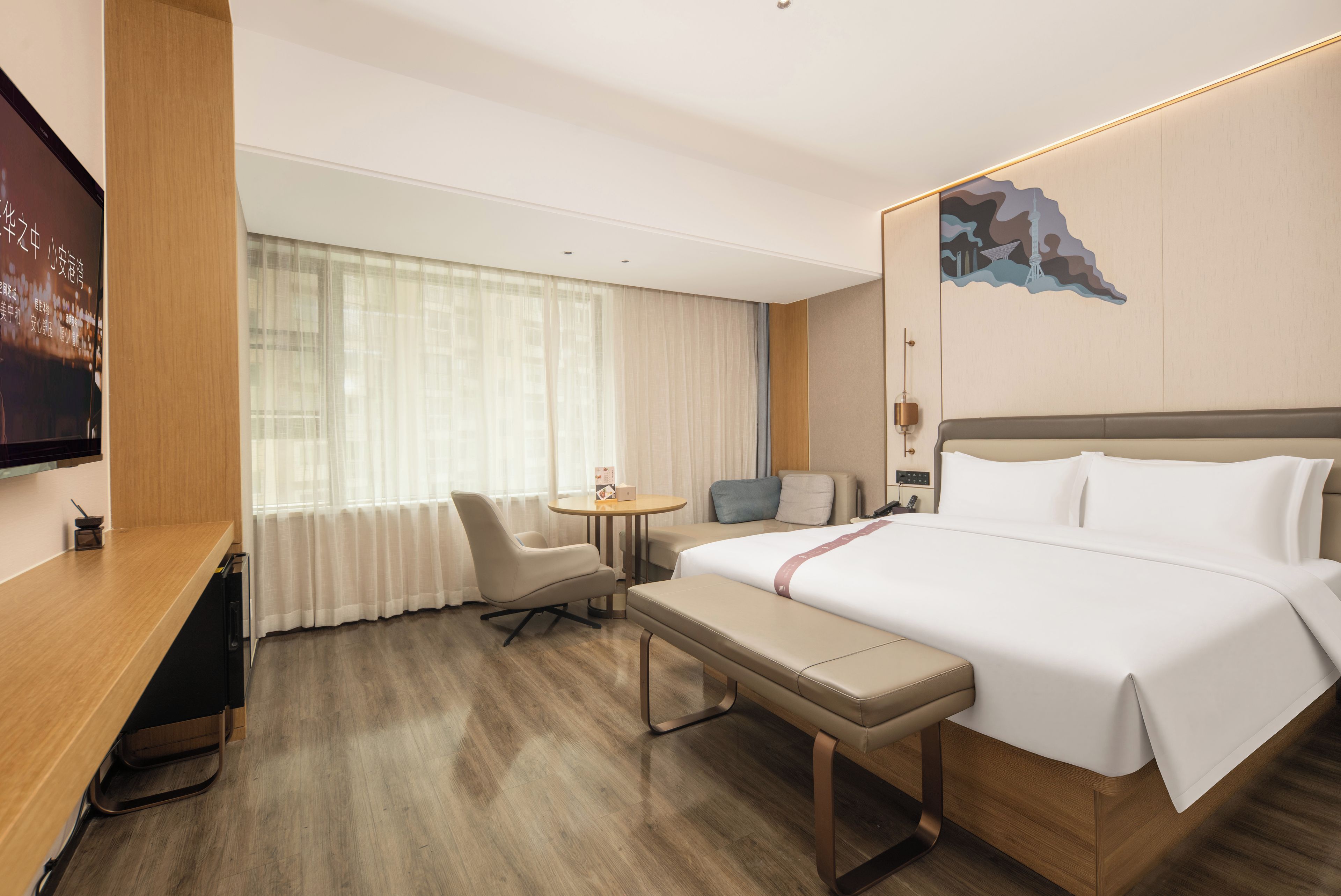 A hotel room with a bed, a desk, a chair, a small table, and a TV.
