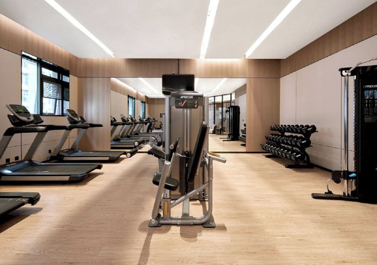 A modern gym with treadmills, weight machines, and dumbbells.