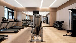 Une salle de sport moderne équipée de tapis de course, d’appareils de musculation et d’haltères.