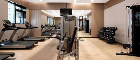 A modern gym with treadmills, weight machines, and dumbbells.