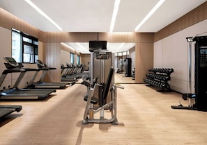 Une salle de sport moderne équipée de tapis de course, d’appareils de musculation et d’haltères.
