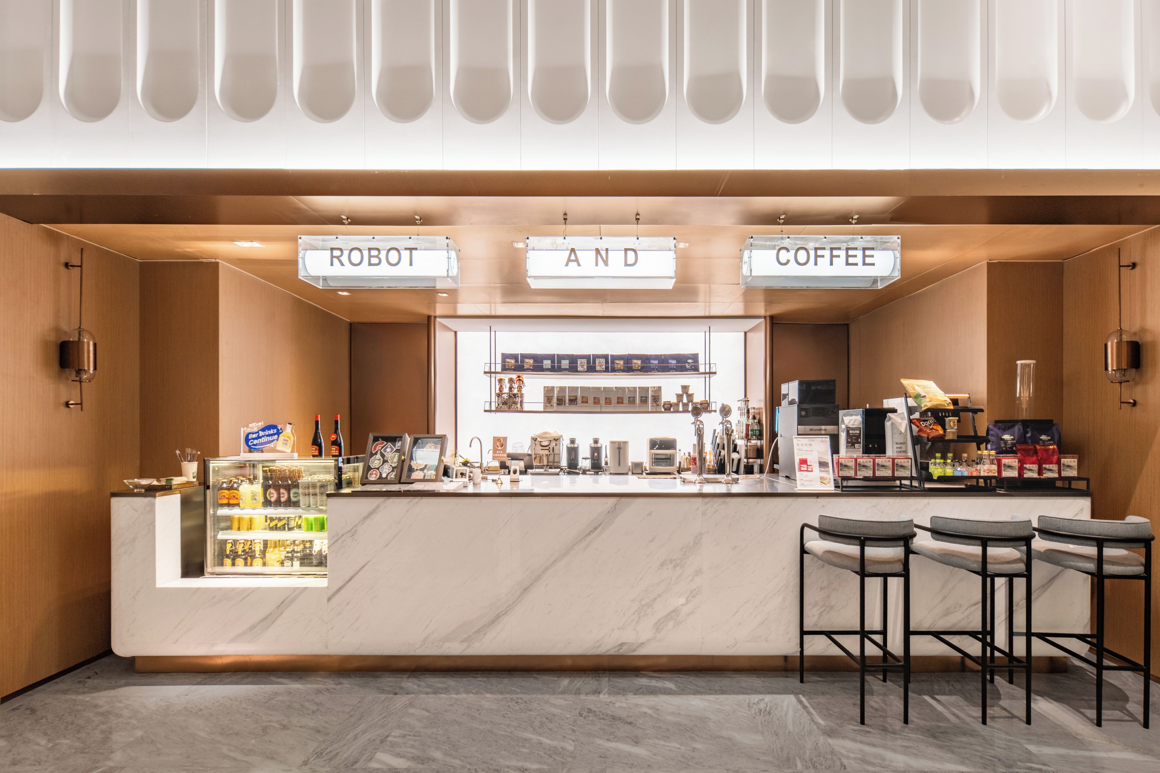 Un café moderne avec un comptoir en marbre, des tabourets de bar et un présentoir où sont exposés différents produits à base de café.