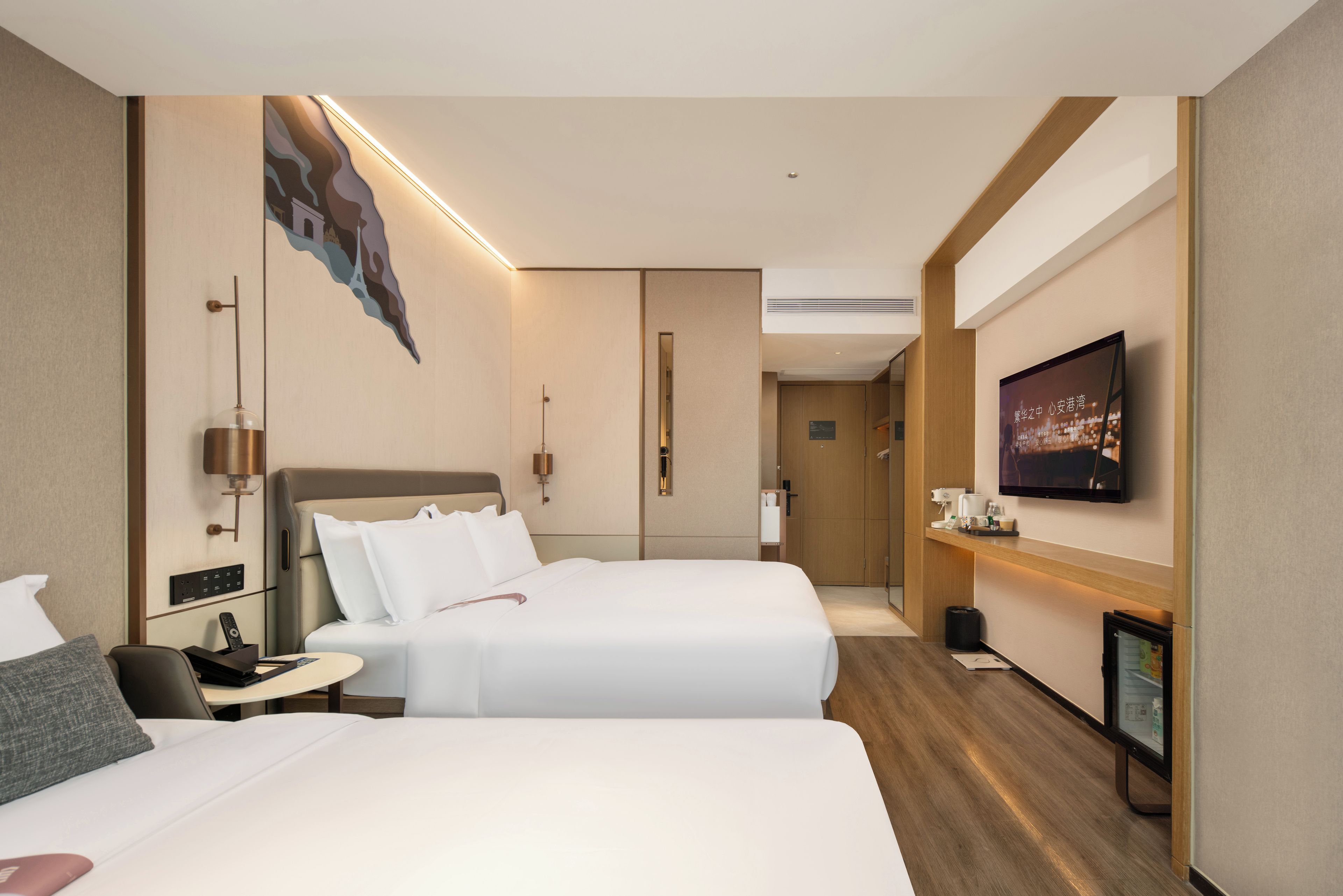 A hotel room with two beds, a television, a desk, and a bathroom visible through an open door.