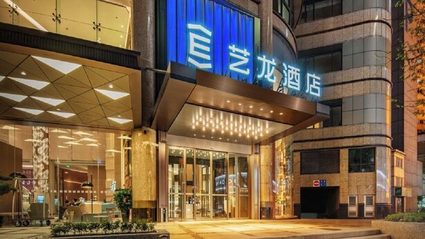 L’entrée d’un hôtel, avec une enseigne bleue, des portes en verre et une architecture moderne.