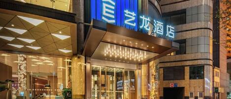 A hotel entrance with a blue sign, glass doors, and a modern architectural design.