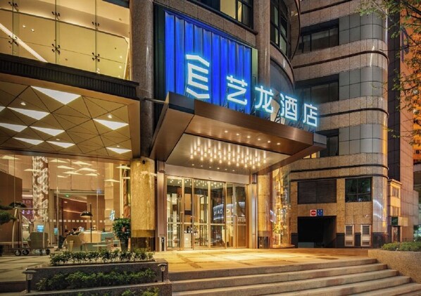 L’entrée d’un hôtel, avec une enseigne bleue, des portes en verre et une architecture moderne.
