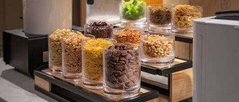Buffet de café da manhã com diversos alimentos em recipientes transparentes.