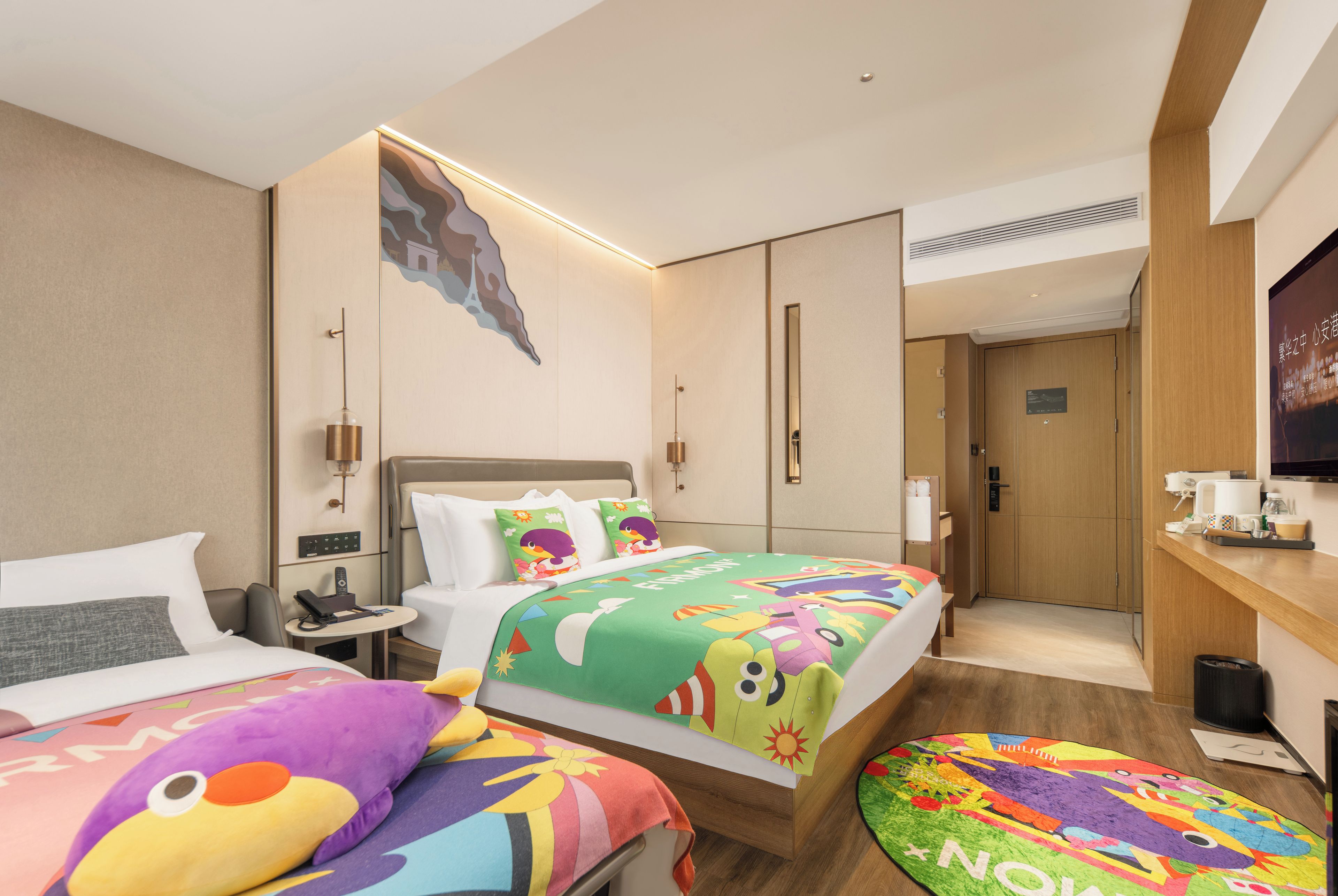 Habitación de hotel con dos camas, una mesita, un sofá, un televisor y la puerta del baño.