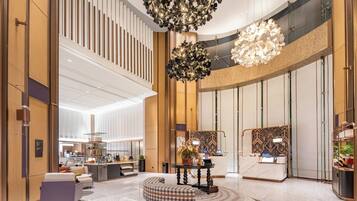 A spacious lobby with a high ceiling, a central seating area, and a reception desk.