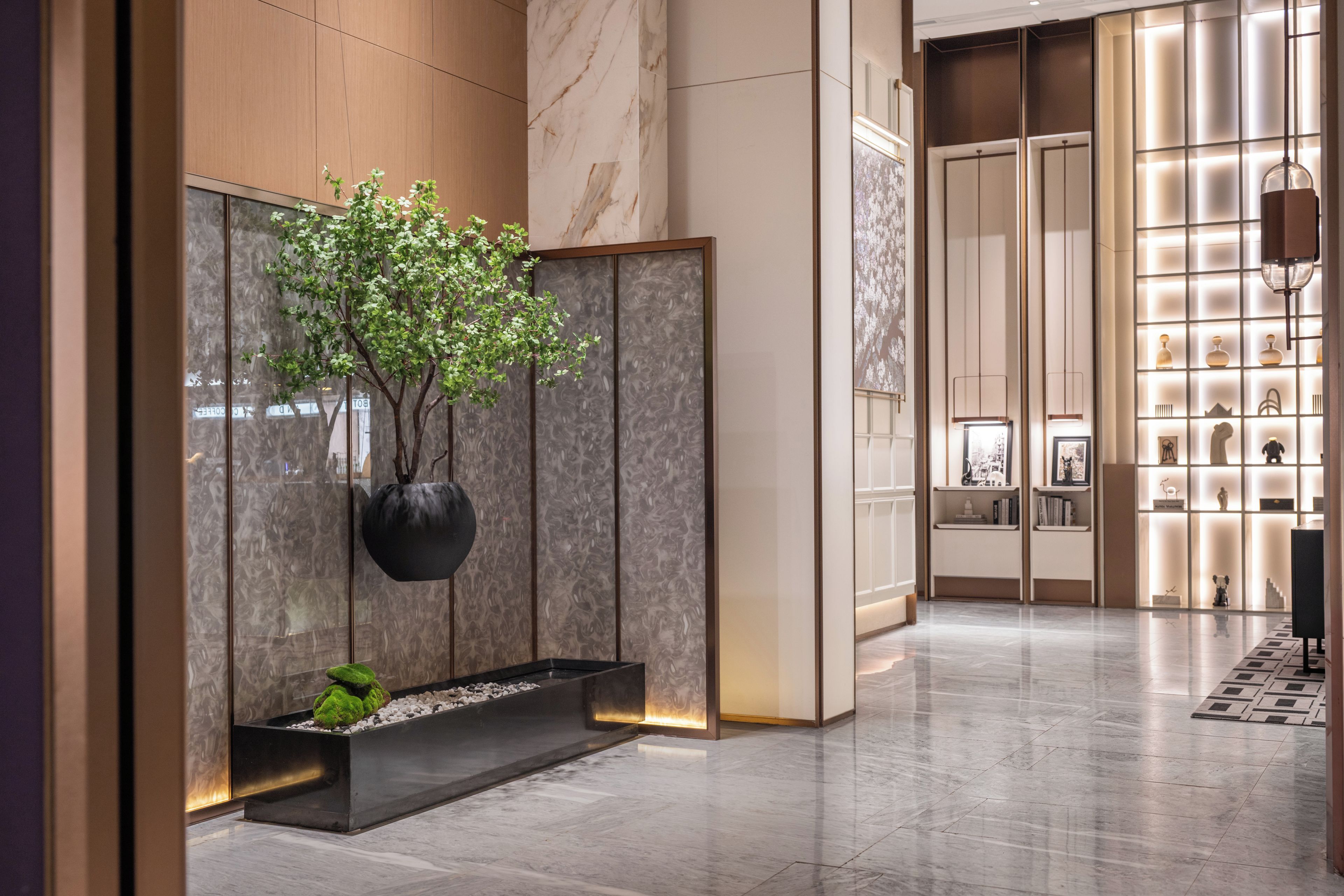 A modern lobby with a marble floor, a potted plant, and a display of decorative items.
