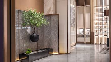 A modern lobby with a marble floor, a potted plant, and a display of decorative items.