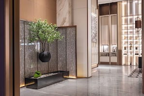 A modern lobby with a marble floor, a potted plant, and a display of decorative items. - Shanghai Elong Hotel by the Nanjing Road (Shanghai)