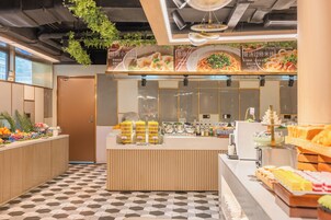 A modern cafe with a checkered floor, a wooden counter with a glass display, and a menu above.
