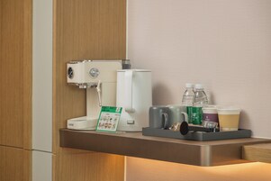A coffee machine, water bottles, and a tray with mugs and cups on a counter.