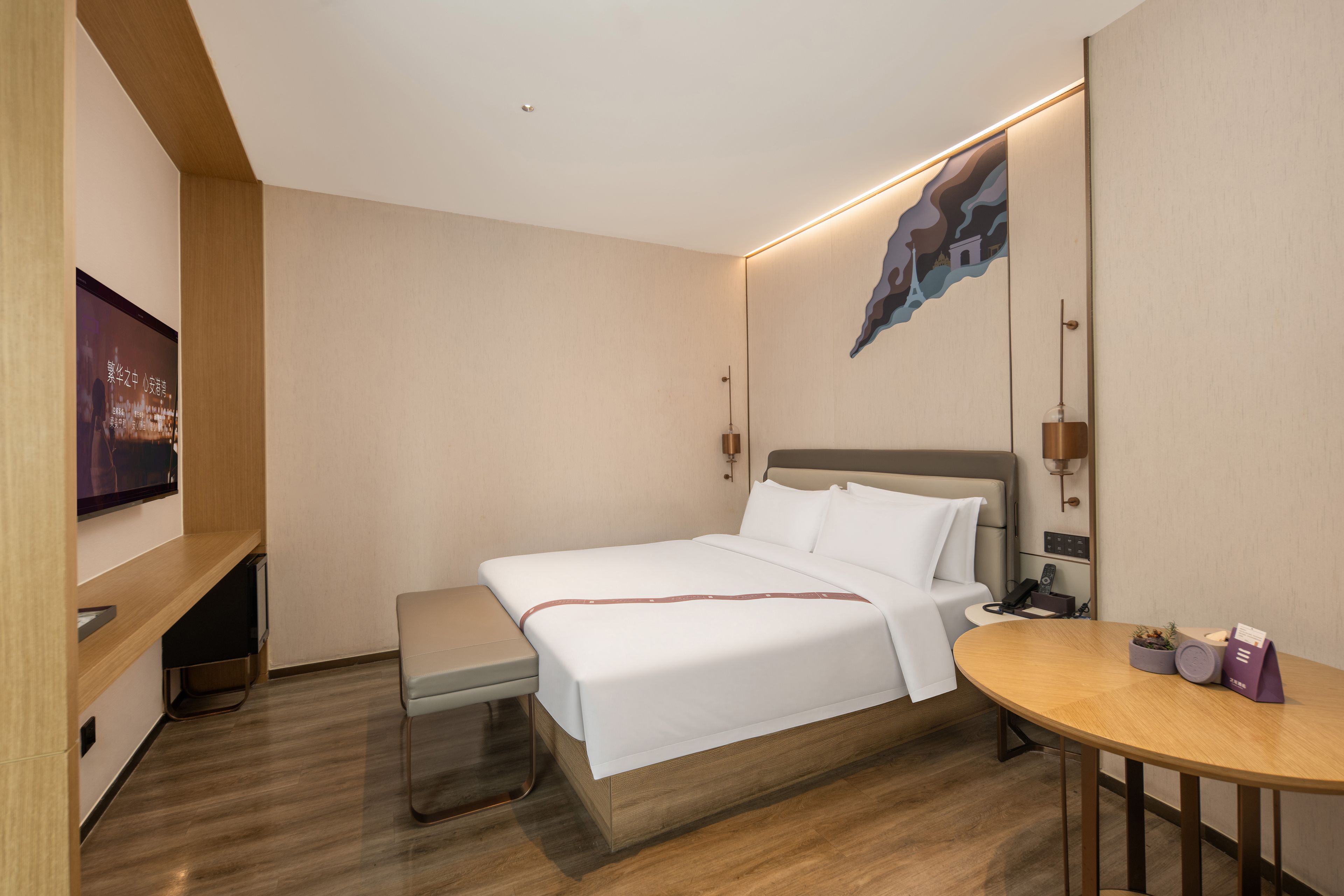A hotel room with a bed, bedside table, and a TV mounted on the wall.