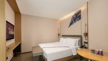 A hotel room with a bed, bedside table, and a TV mounted on the wall.