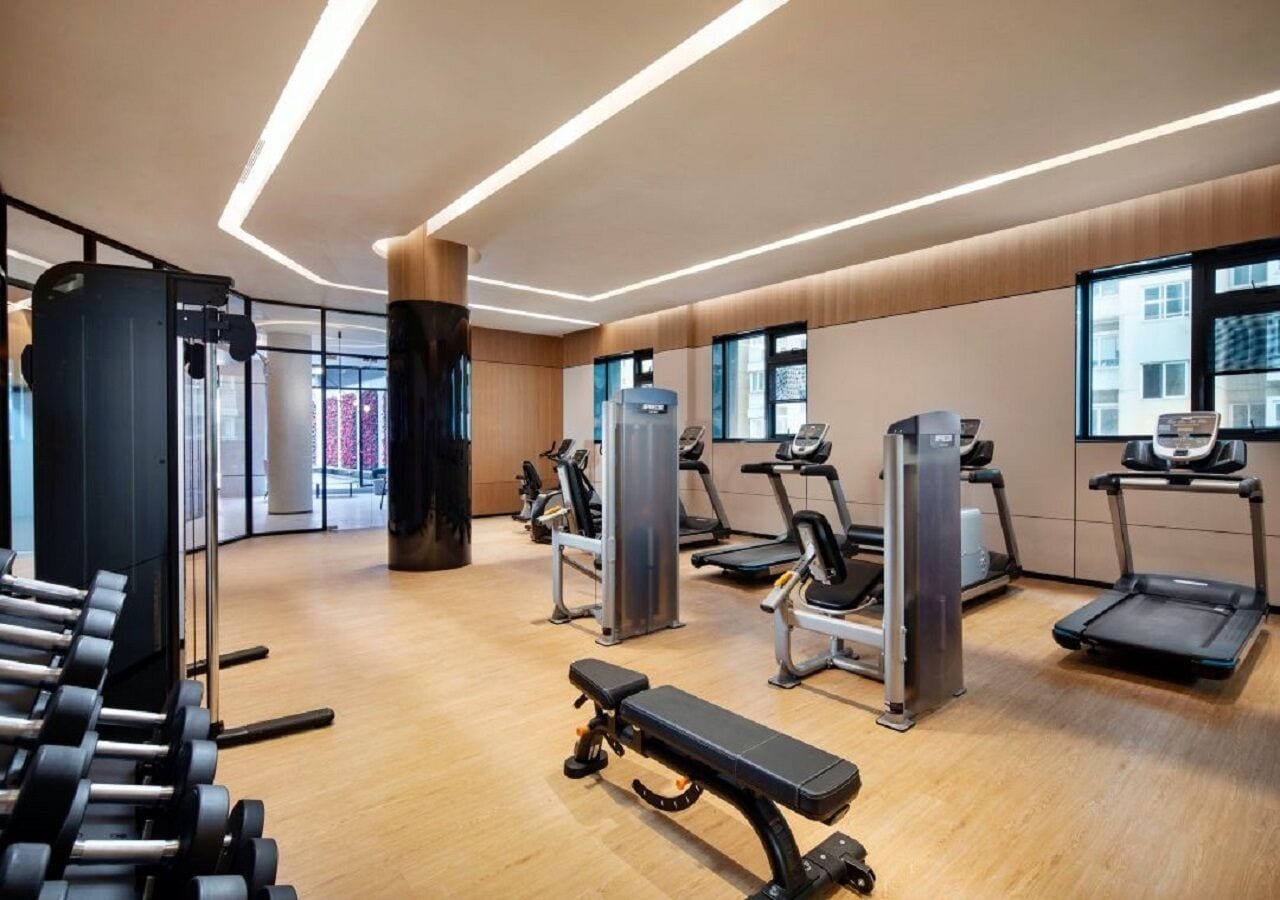 Een moderne sportschool met diverse fitnessapparaten, waaronder loopbanden, krachtapparaten en gewichten.