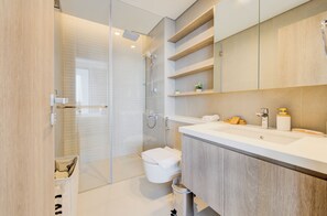 A modern bathroom with a glass-enclosed shower, a white toilet, and a vanity with a mirror and shelves.
