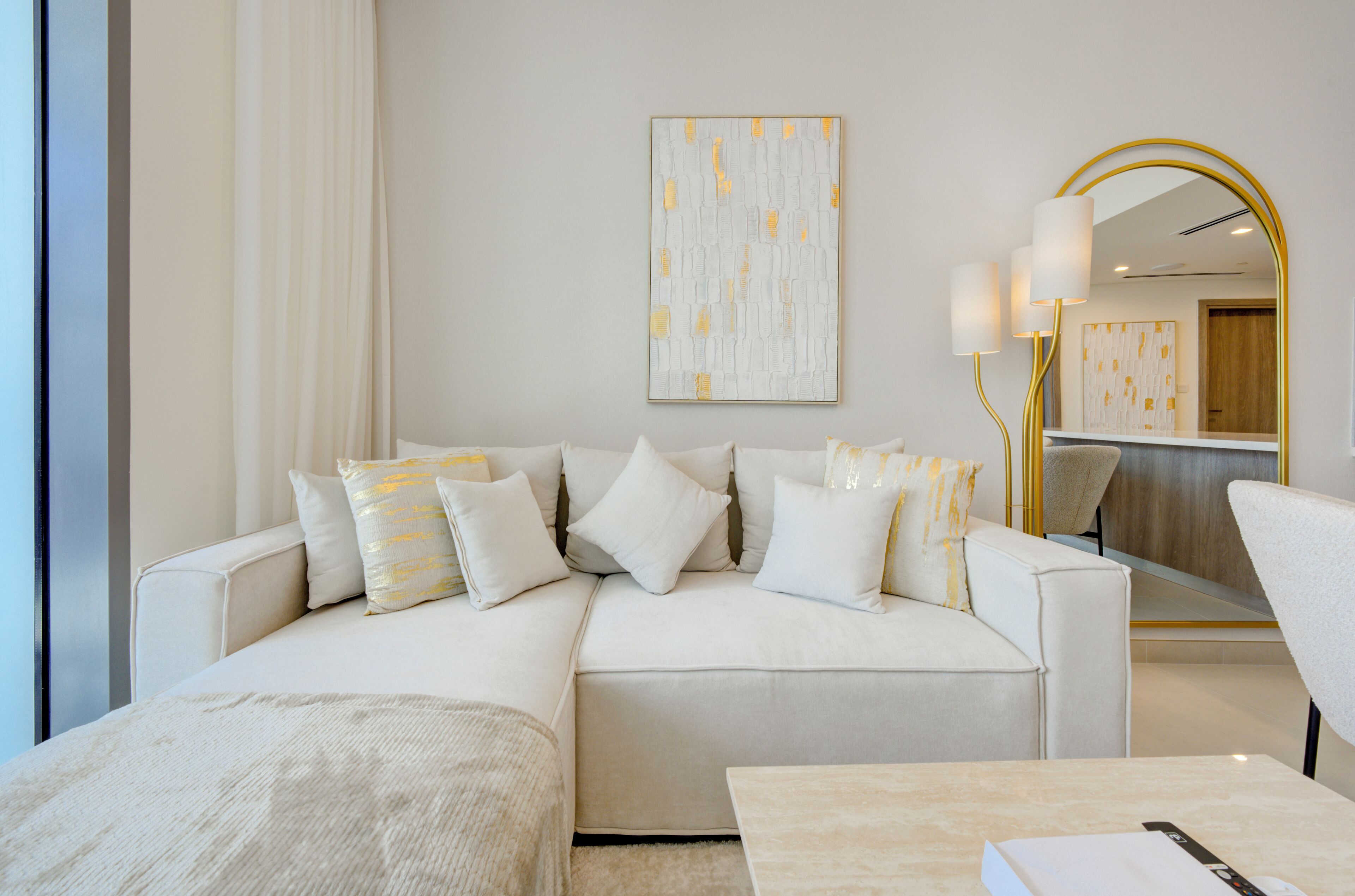 A modern living room with a sofa, a coffee table, and a large mirror with a gold frame.