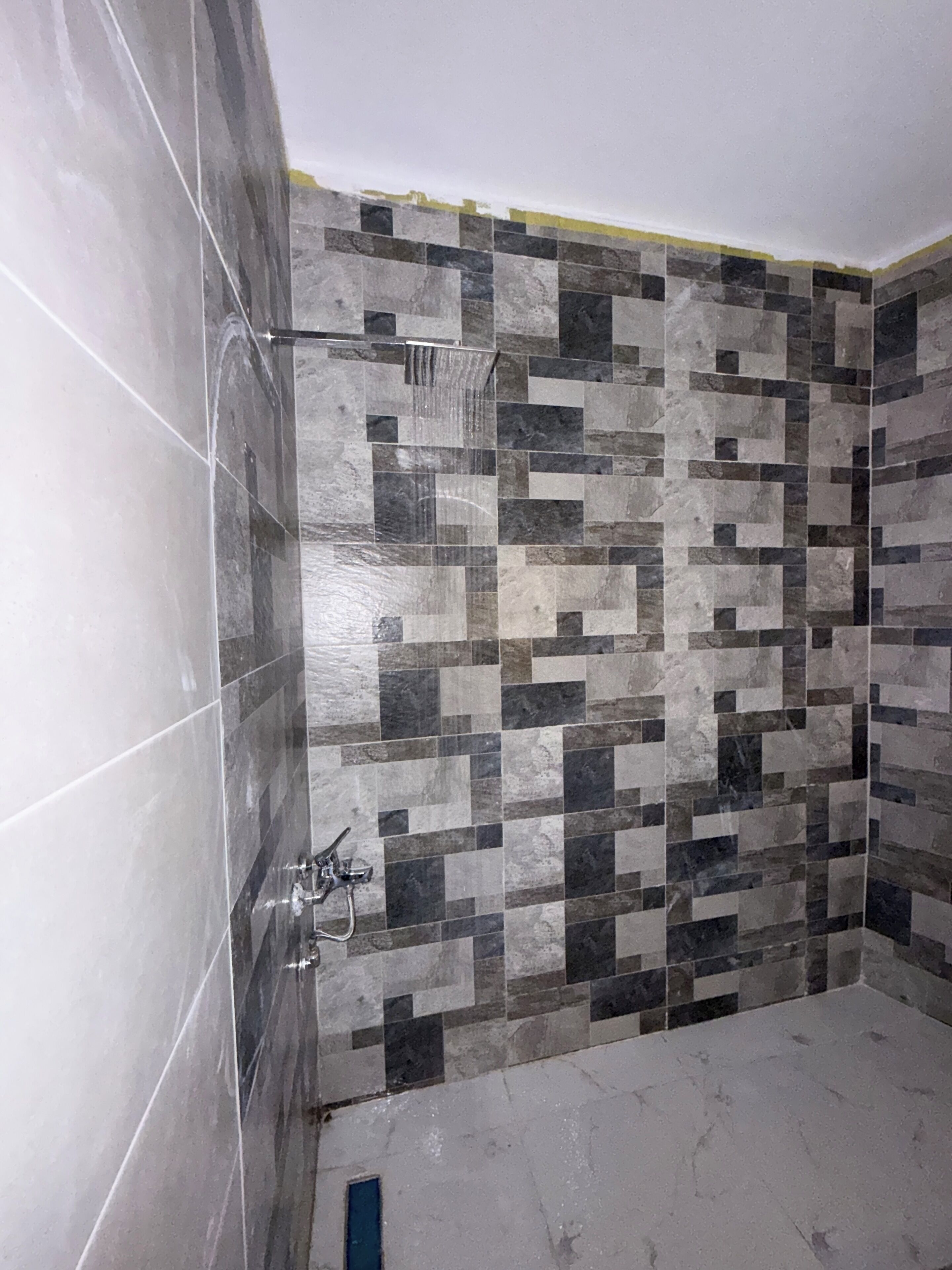Un baño con pared de ducha azulejada y ducha visible.