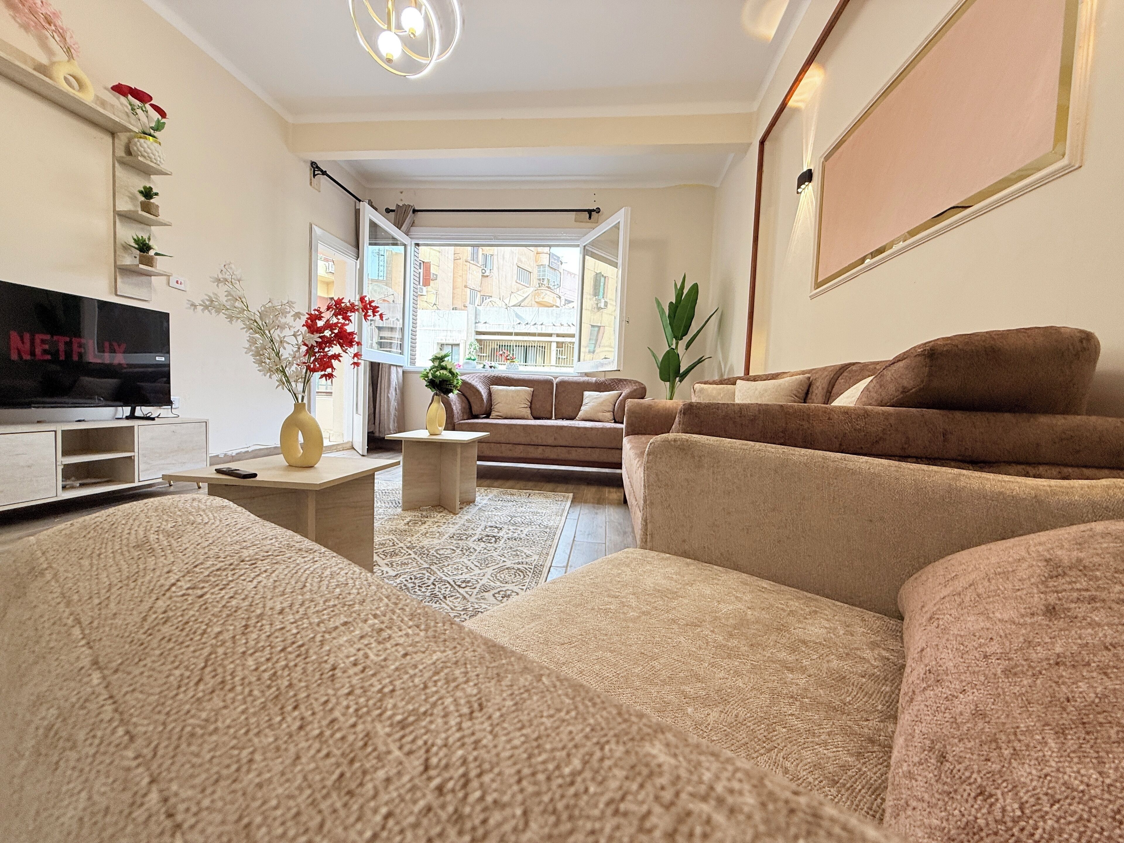 A modern living room with a flat-screen TV, a sofa, a coffee table, and decorative plants.