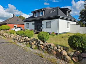 Ein modernes, zweistöckiges Haus mit Mauerwerk, einem gepflasterten Einfahrt und ordentlich gestutzten Hecken.